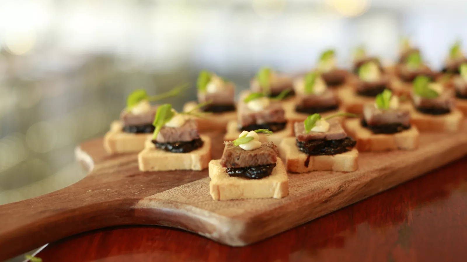 Mini toast canapes served on a wooden board