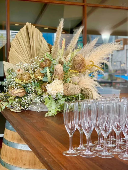 Group of empty sparkling wine glasses in front of a flower display