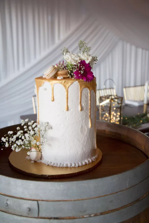 Large white wedding cake with gold decoration and flowers