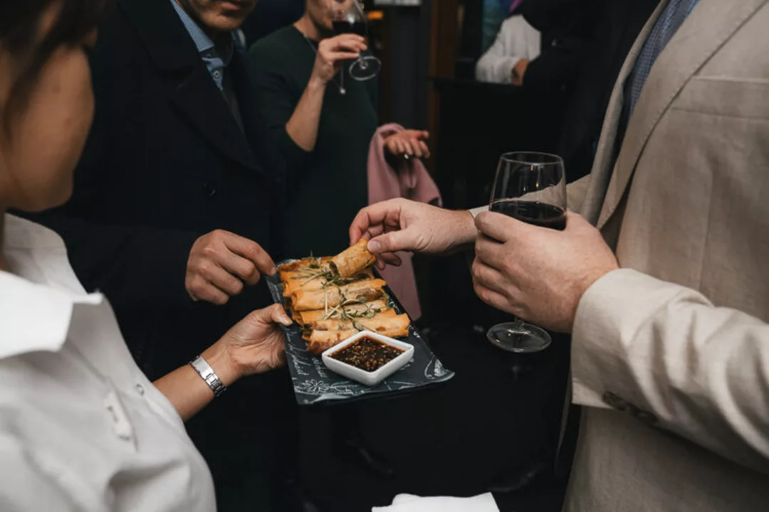 Waiter offers spring rolls to function guests