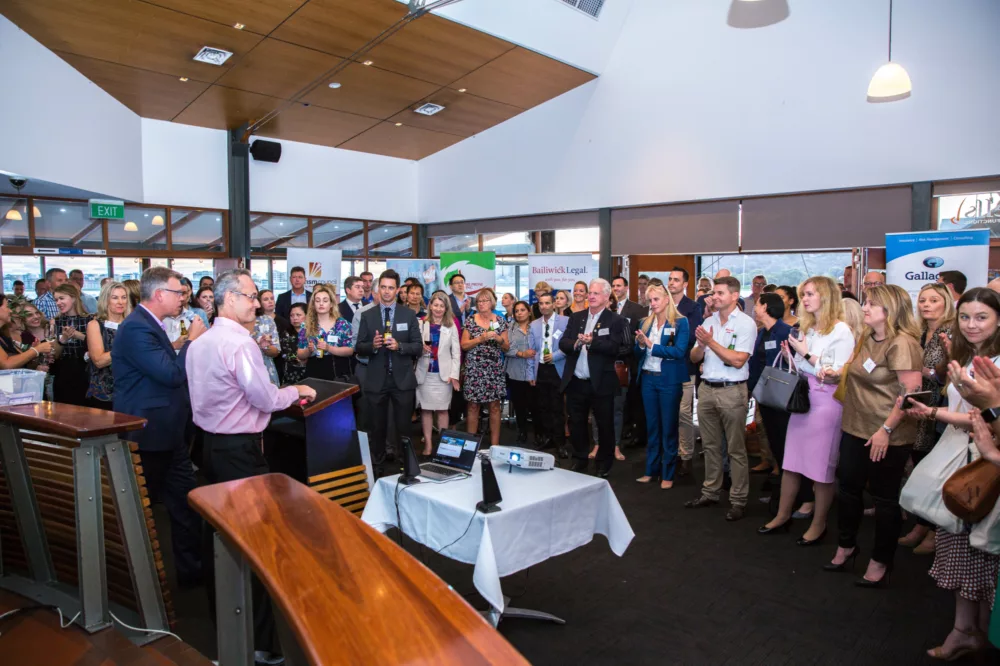 Group of people standing around to listen to a speaker at a business function