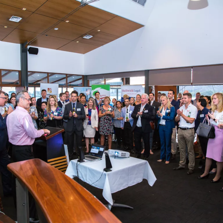 Group of people standing around to listen to a speaker at a business function