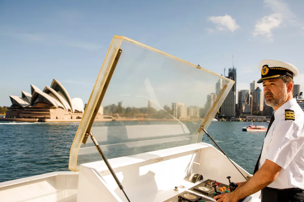 Captain crew driving boat outside past Opera House and Circular Quay