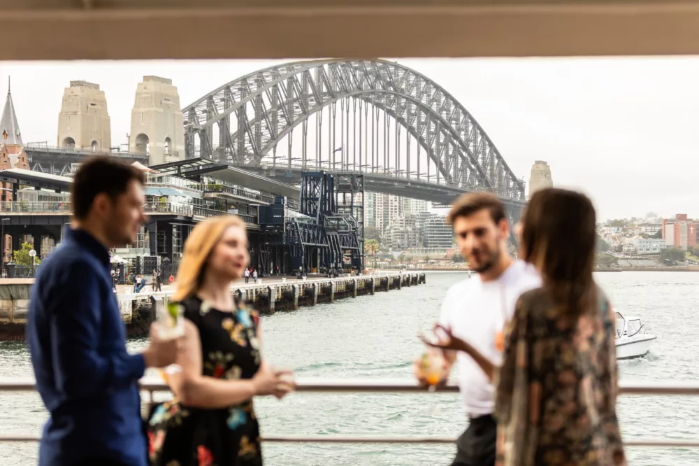 Group of friends having cocktails with Harbour Bridge in the background