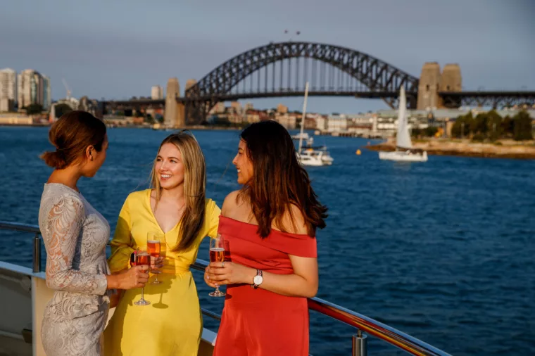Group of girls enjoying pink champagne on the open deck with Harbour Bridge and Barangaroo in the background, christmas party