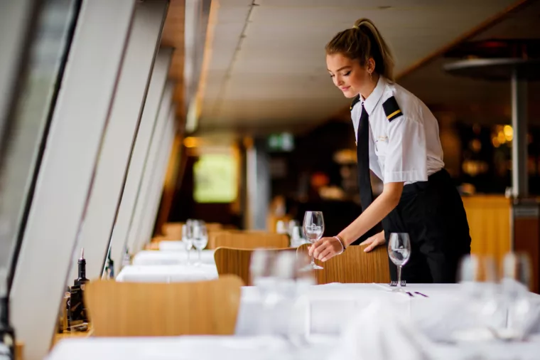 Waitress crew setting up dining table with Gold wine glasses on Sky Deck