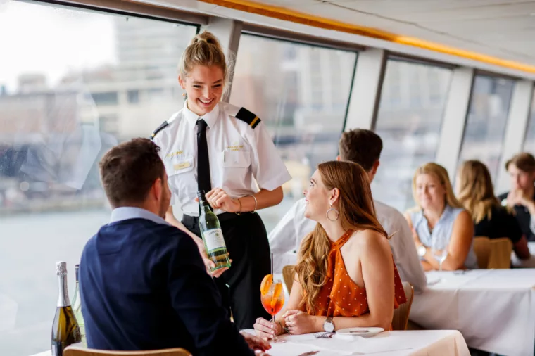 Waitress crew serving Tyrrells Wines to Top Deck Lunch couple with Circular Quay background