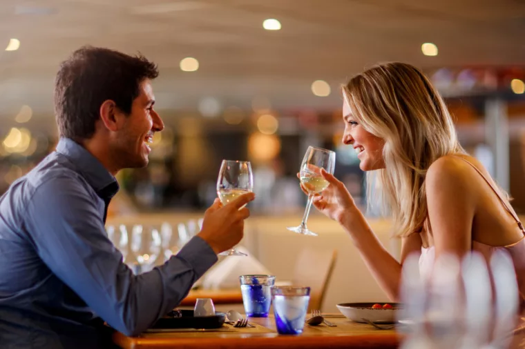 Couple laughing and dining drink white wine for lunch or dinner