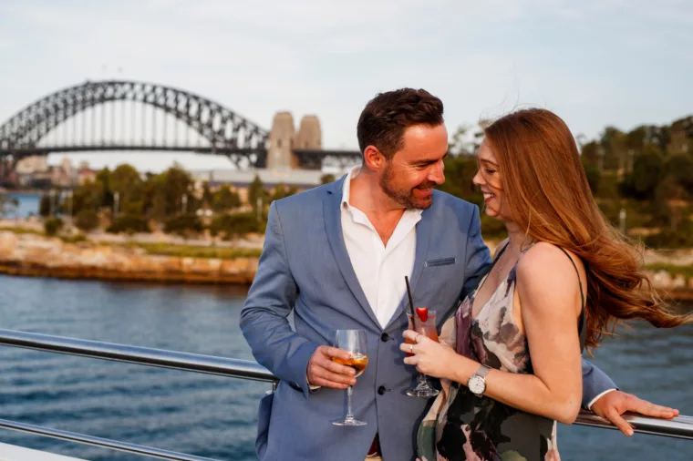 Premium couple having champagne wine outdoors with Harbour Bridge and Barangaroo on the background