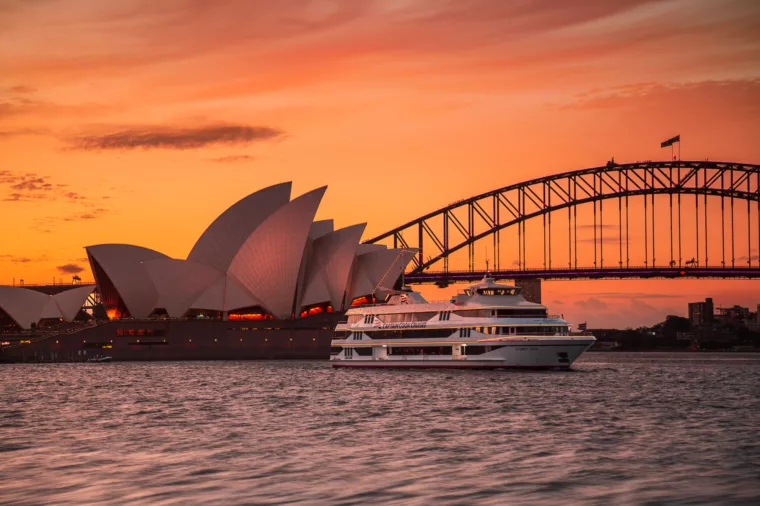 Landscape of Sydney 2000 boat cruising past Opera House and Harbour Bridge at sunset