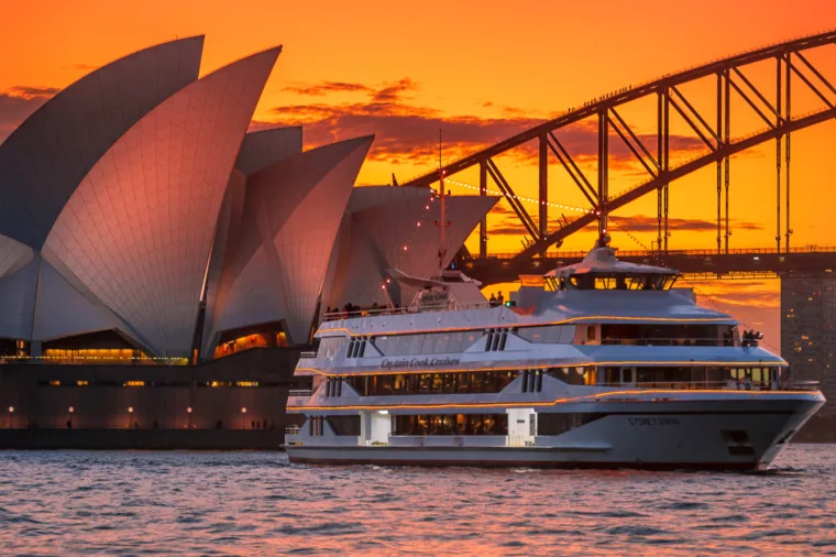 Portrait of Sydney 2000 boat cruising past Opera House and Harbour Bridge at sunset