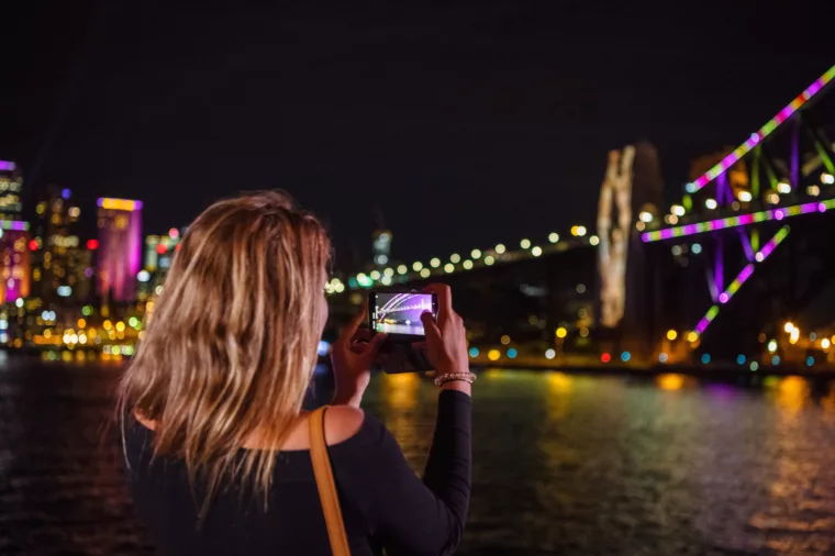 Girl taking selfie picture of Harbour Bridge during Vivid special event at night dining non-ccc dnsw