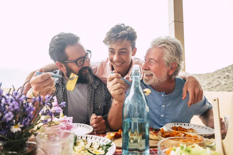Boys group with grandfather senior, father and son dining - stock