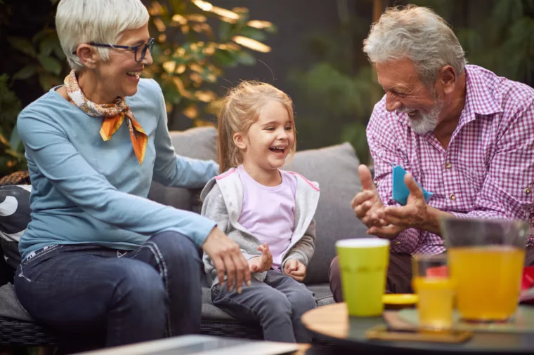 Senior grandparent couple with grand daughter child on lounge