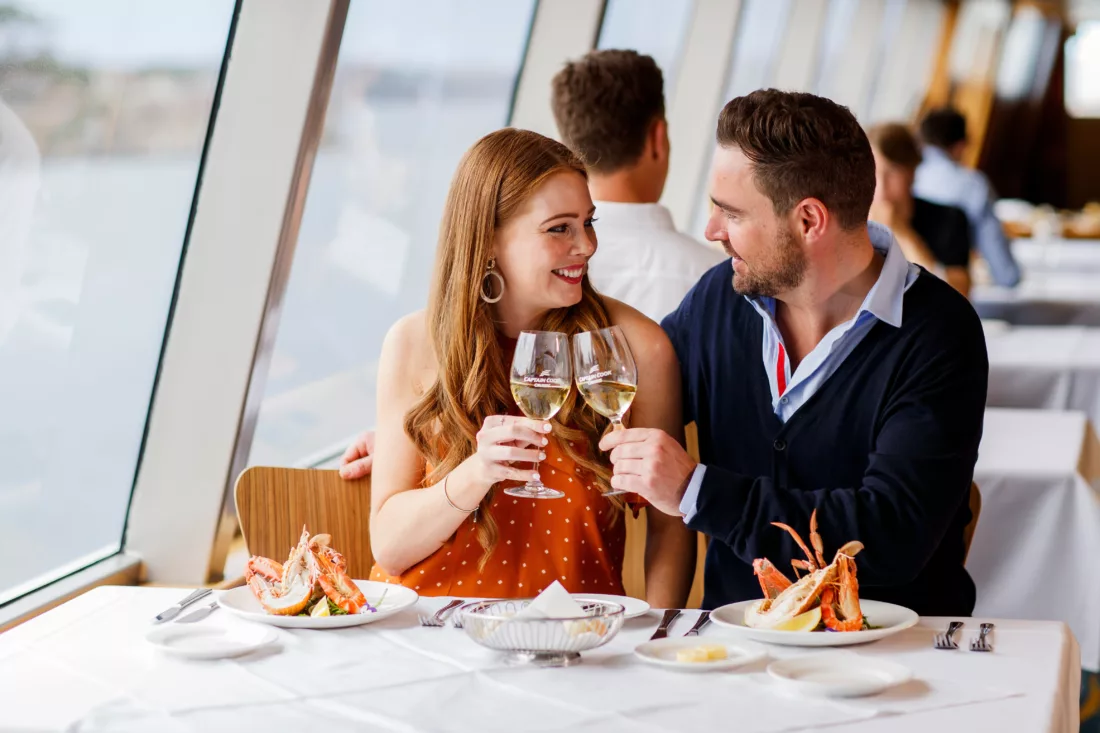 Couple toasting white wine and eating seafood day time Top Deck Lunch