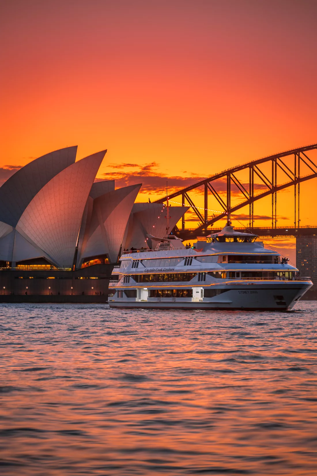 Portrait of Sydney 2000 boat cruising past Opera House and Harbour Bridge at sunset