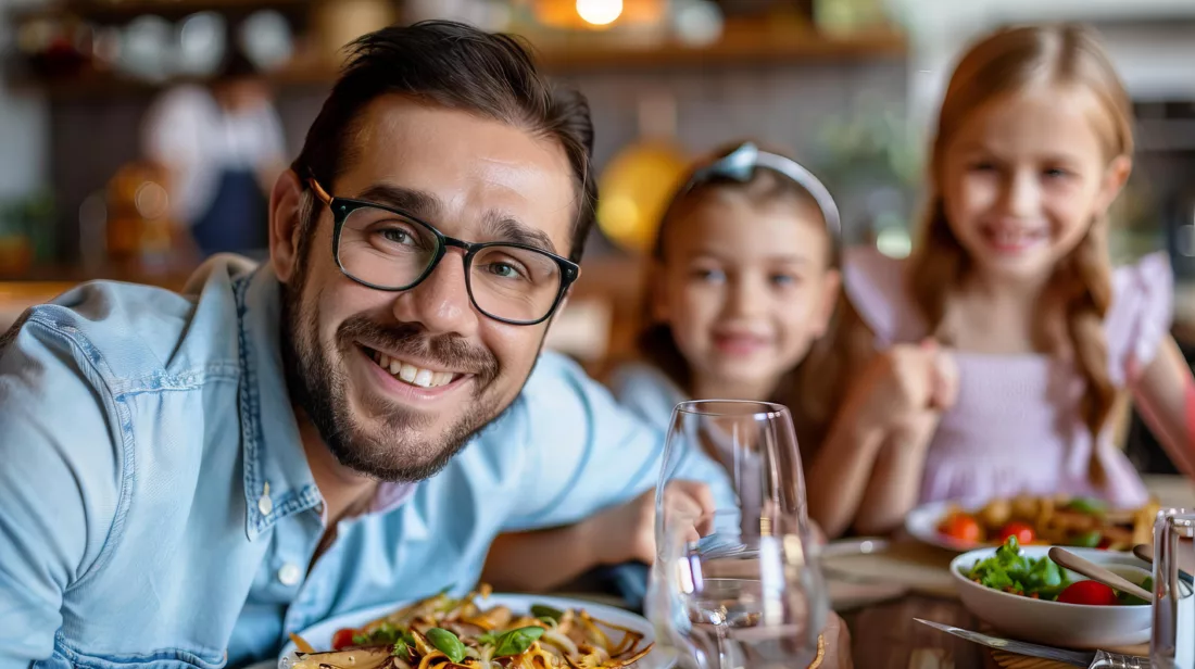 Cheerful father sharing a meal with his daughters. Happy family enjoying quality time together. Father's Day.