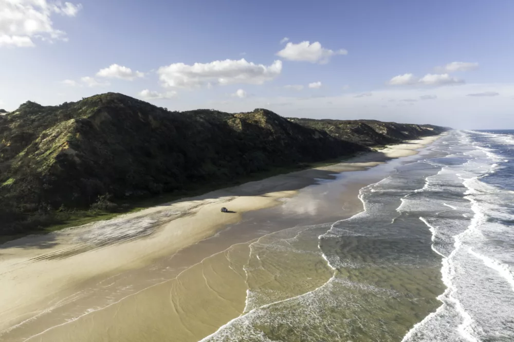 Aerial of 4WD driving along 75 Mile Beach, K'gari (Fraser Island)