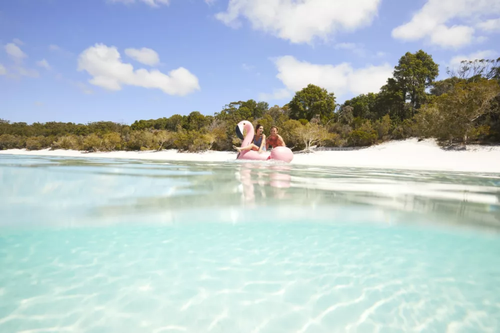 Couple floating on pink Flamingo in Lake McKenzie, K'gari (Fraser Island)