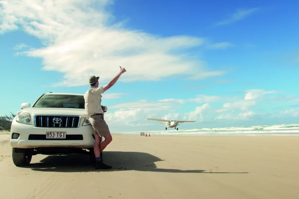 Man waving at plane landing on 75 Mile Beach, K'gari (Fraser Island)