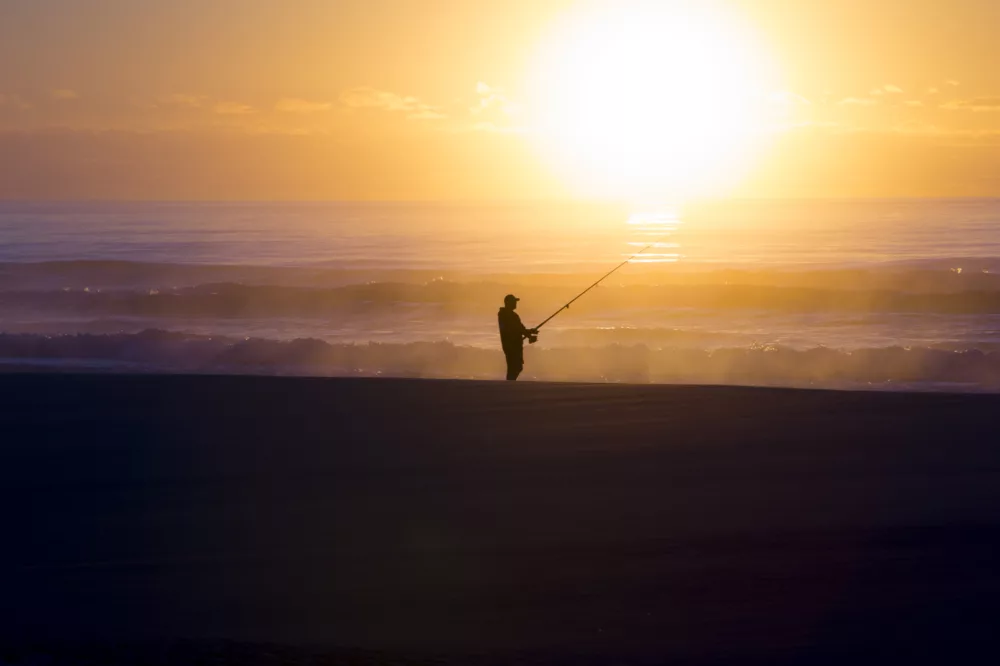 Man fishing at sunrise on beach, K'gari (Fraser Island)