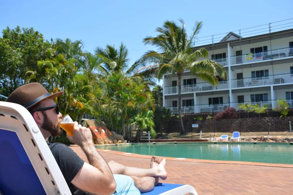 Man drinking a refreshing beer poolside at K'gari Beach Resort, K'gari (Fraser Island)