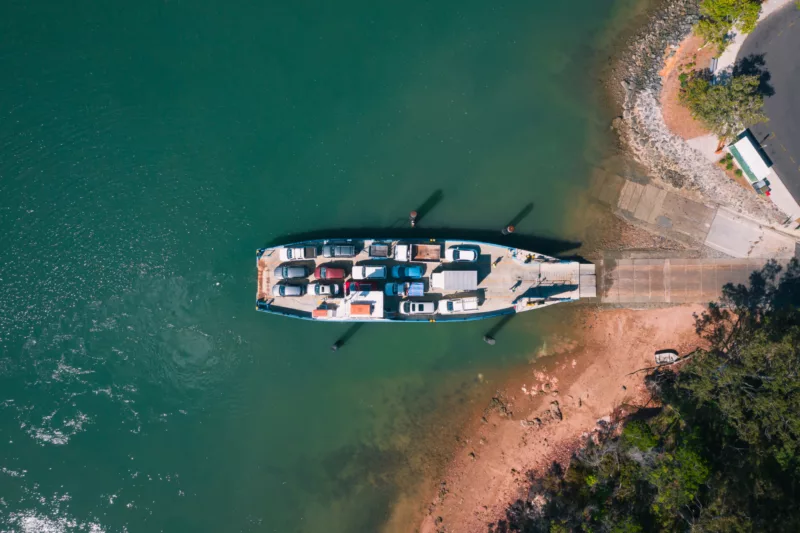 An aerial shot of a vehicle ferry transporting cars across to the island
