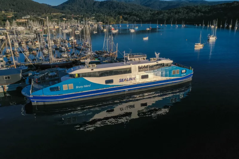 An aerial shot of a white and blue ferry moored near the dock