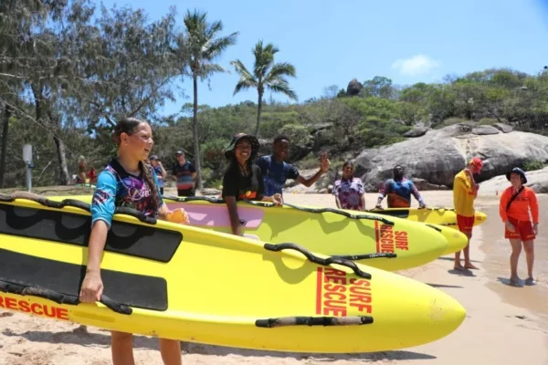 Image showcasing NRL Cowboys House students with surfboards.