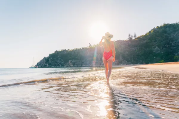 A woman in a red swimsuit walks on the beach at Magnetic Island