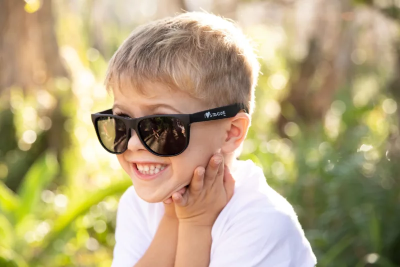 A boy wearing black sunnies with I love Straddie printed on them