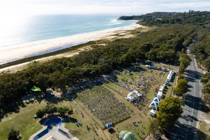 A drone image overview of the Point Lookout oval set up for the Straddie Salute Triathalon with bike racks, tents and flags