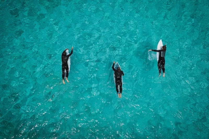 Aerial view of three surfers in the water at Rottnest Island Authority