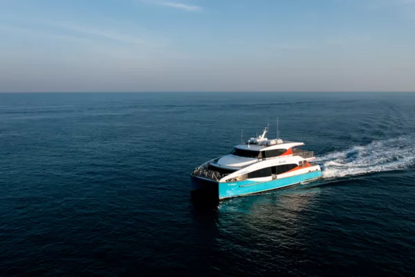A white and blue ferry sails in the ocean