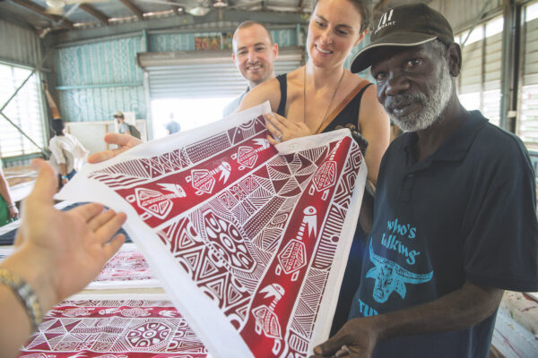A Tiwi Island local artist showcases a screen-printed fabric in red and white