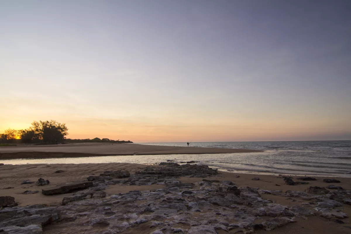 A man fishing on the beach at sunset in Mandorah