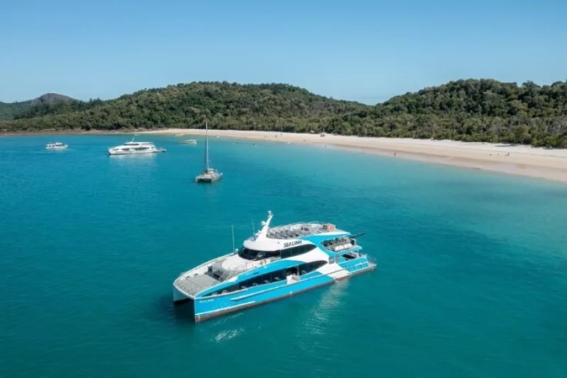 A white and blue ferry anchored in the blue ocean