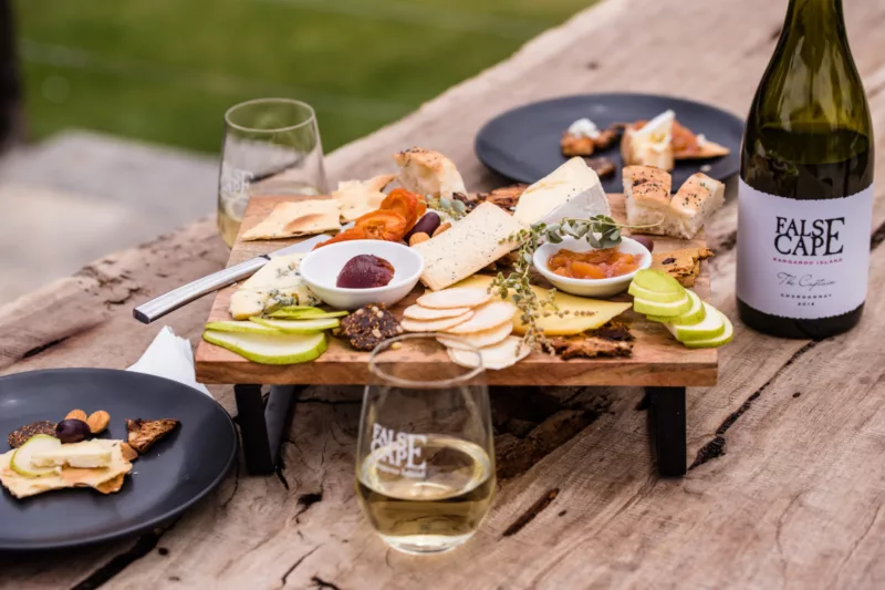 A cheeseboard and a bottle of wine on a wooden table