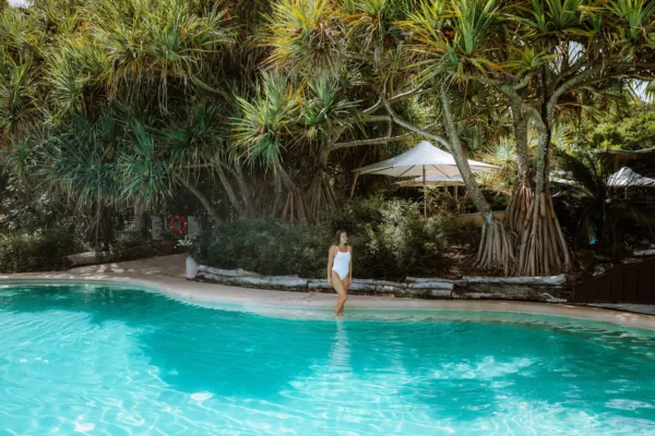 A woman standing in the water on the edge of a swimming pool.