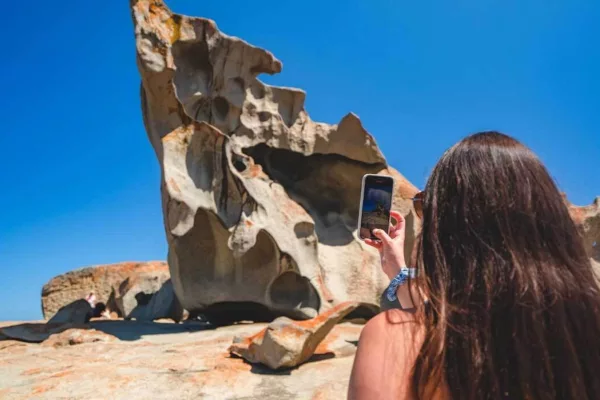 A woman takes a photo of Remarkable Rocks